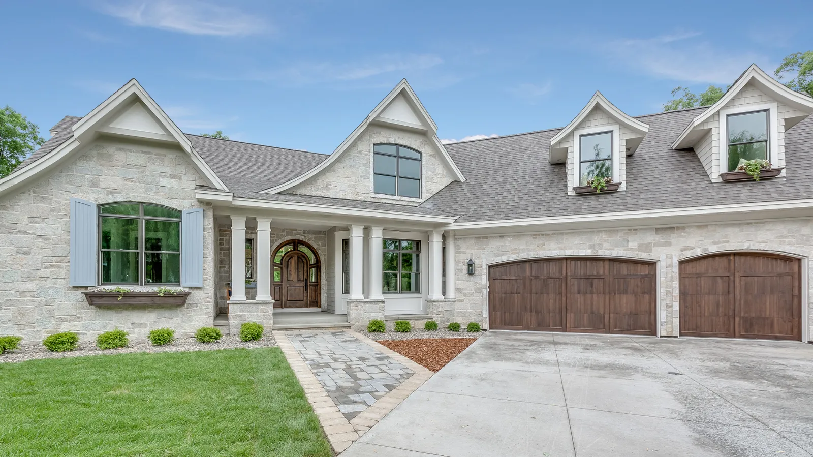 Gray architectural shingle roof over a light stone home with blue shutters