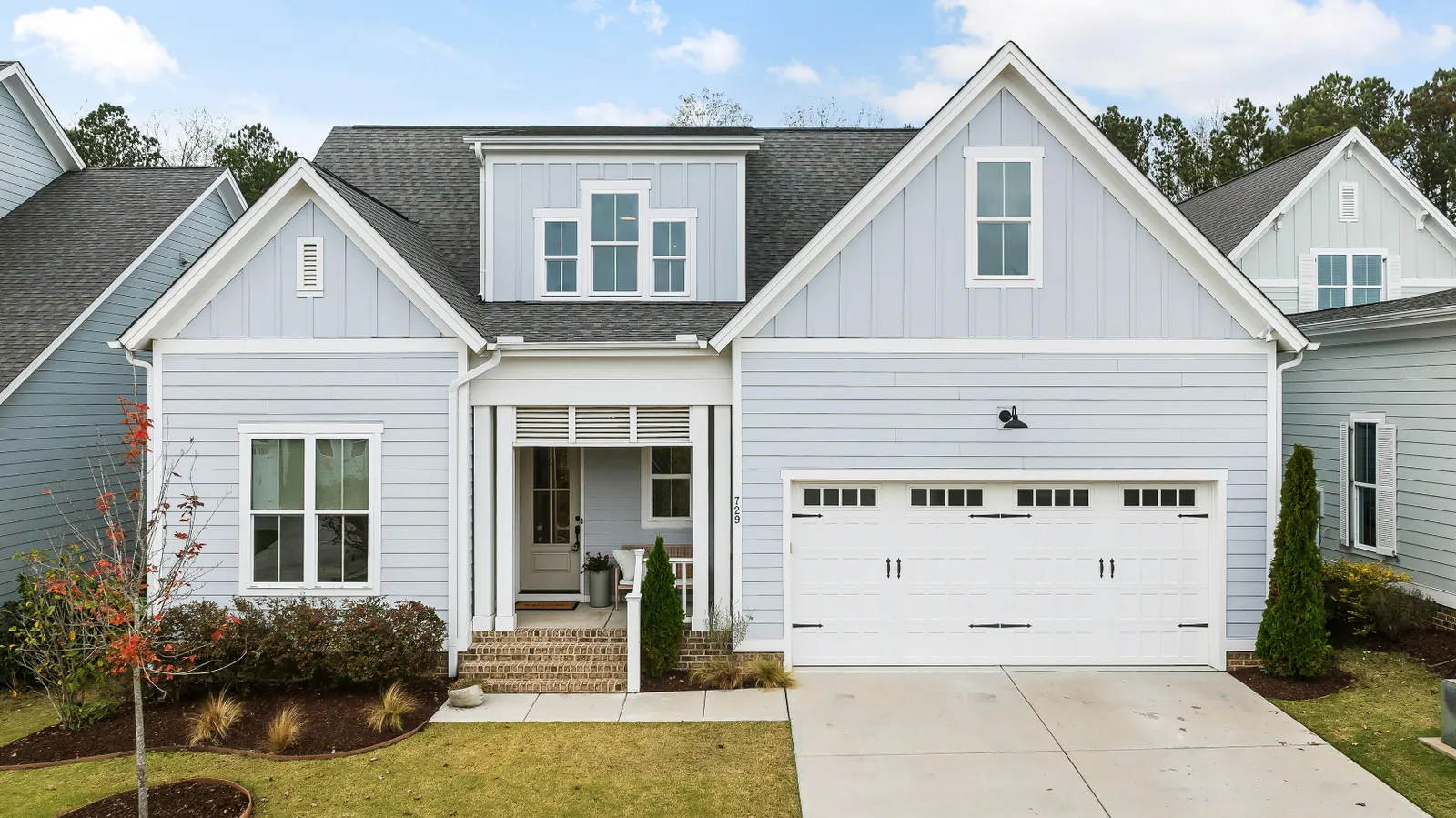 White garage door on a light blue siding home under a gray shingle roof